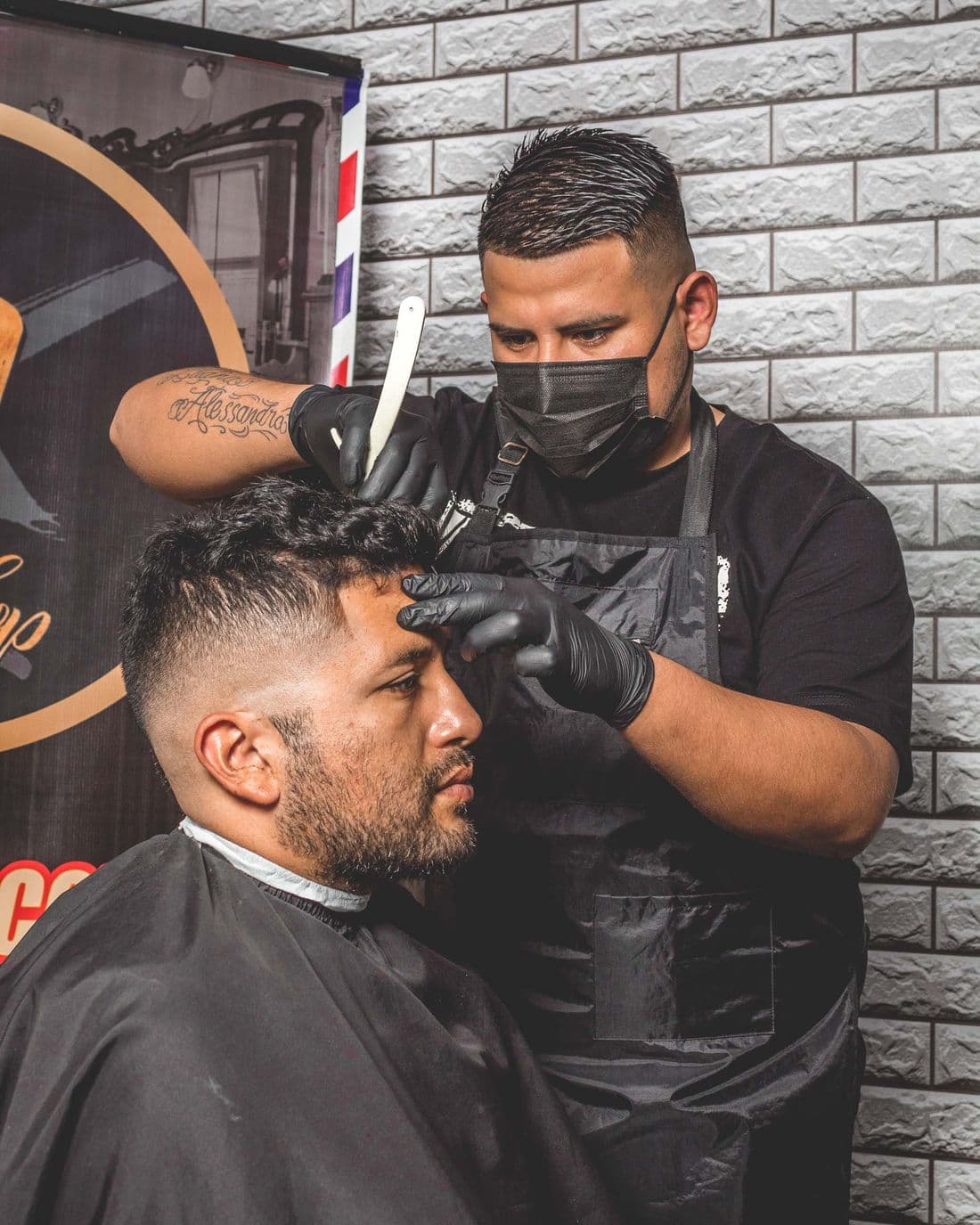 A barber at Tha Cut mid-cut, focused on detail