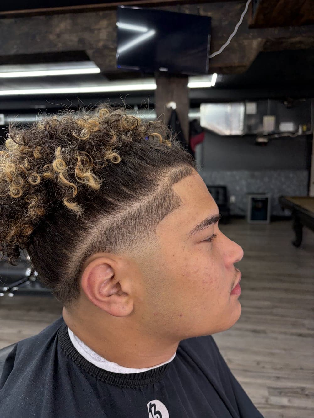 Curly blonde top with a hard part and clean taper