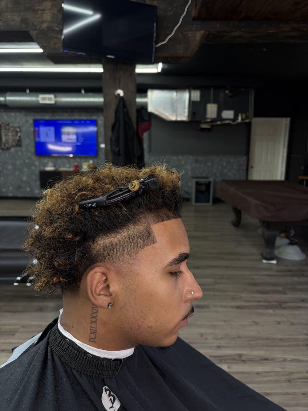 Textured blonde curls with a shaved hard part